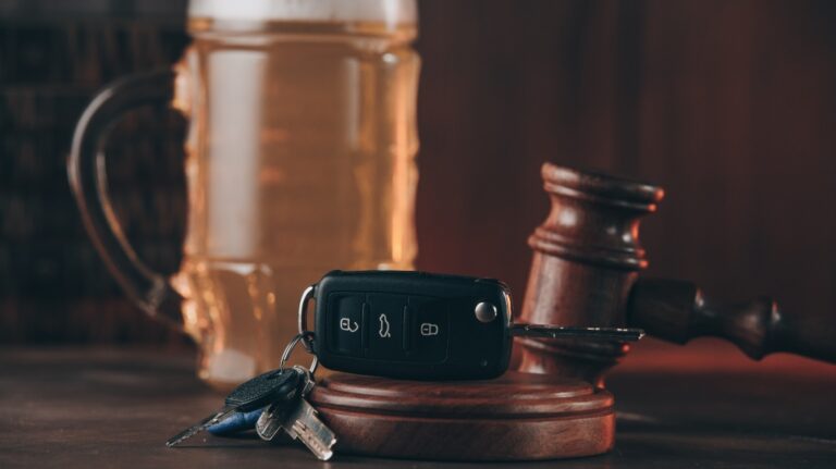 Glass of beer, car keys and judge gavel on a wooden table