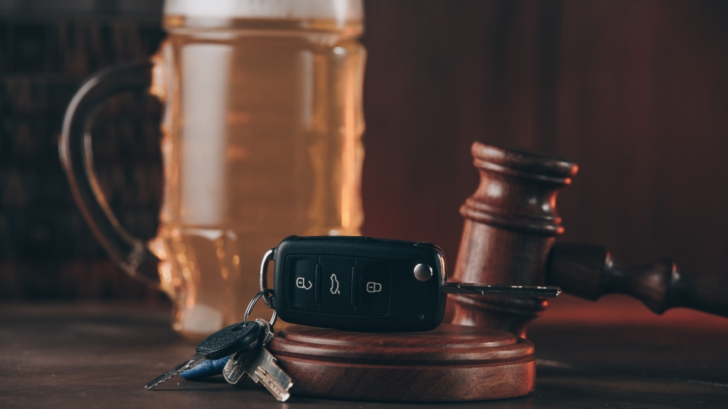 Glass of beer, car keys and judge gavel on a wooden table