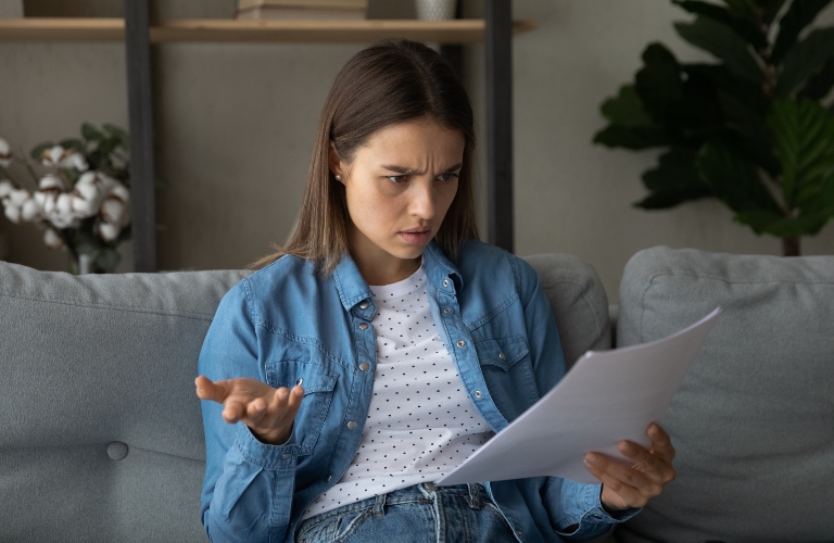 unhappy young woman looking through paper letter